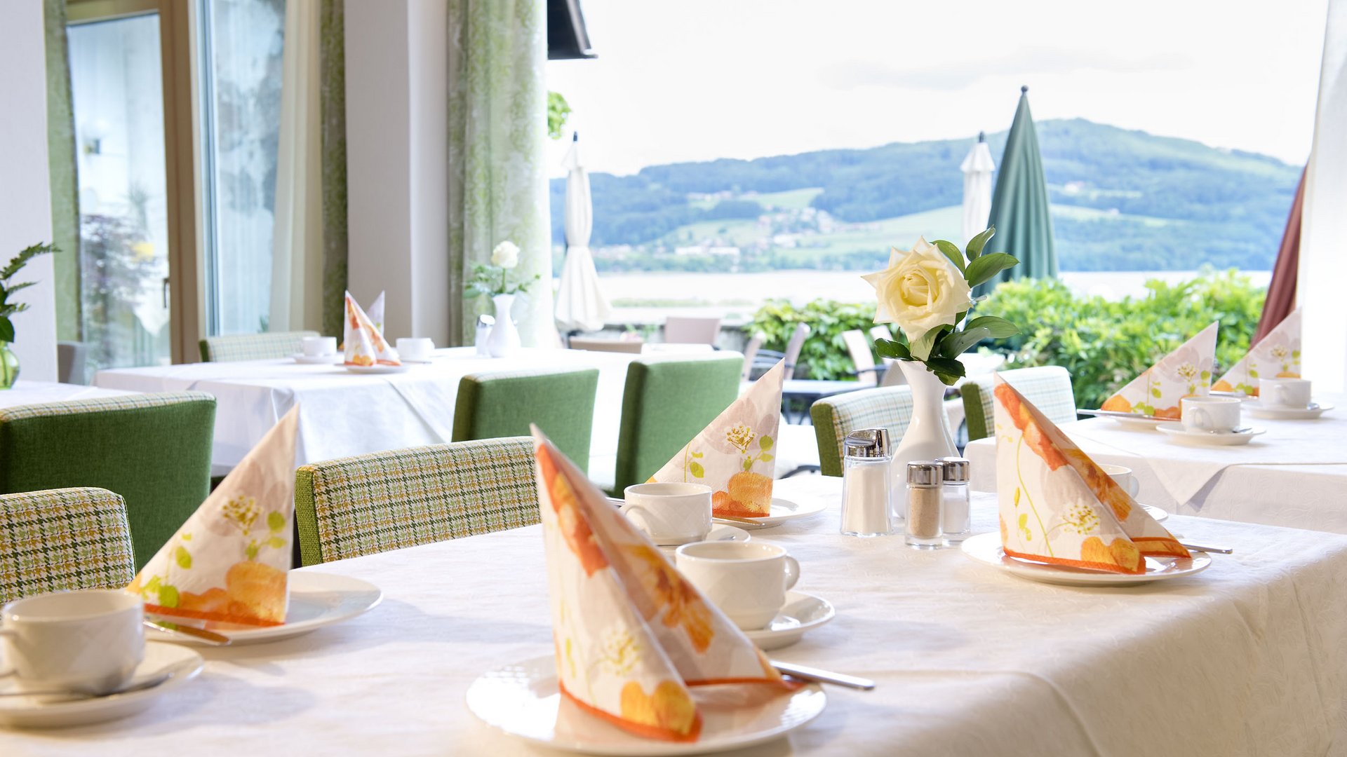 Restaurant table set with napkins and a view of green hills