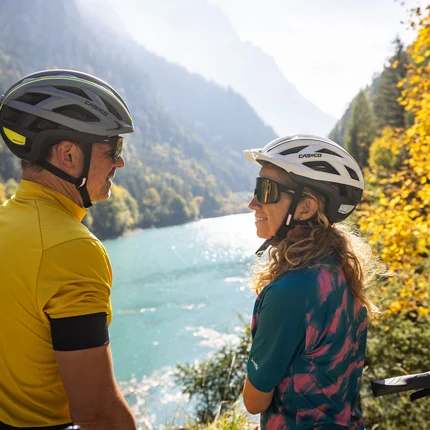 Radfahren im Heidiland: Fünf Ideen für deinen perfekten Radtag © Heiko Mandl Zwei Radfahrer mit Helmen blicken auf einen Fluss in herbstlicher Berglandschaft