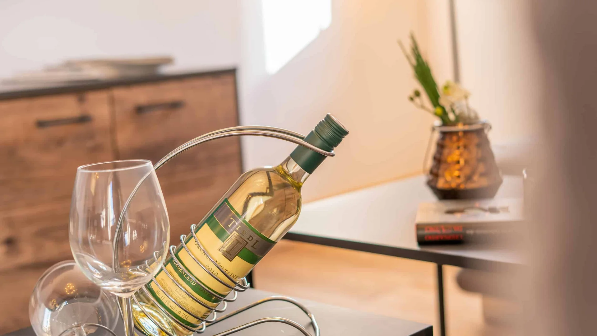 Wine bottle in modern metal holder with two wine glasses on table