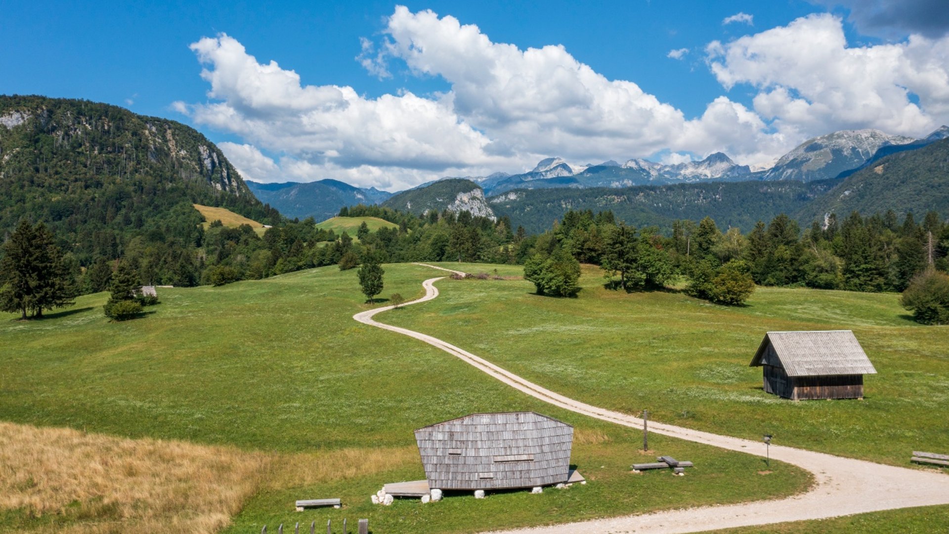 Scenic landscape with mountains, forested hills, and small wooden huts