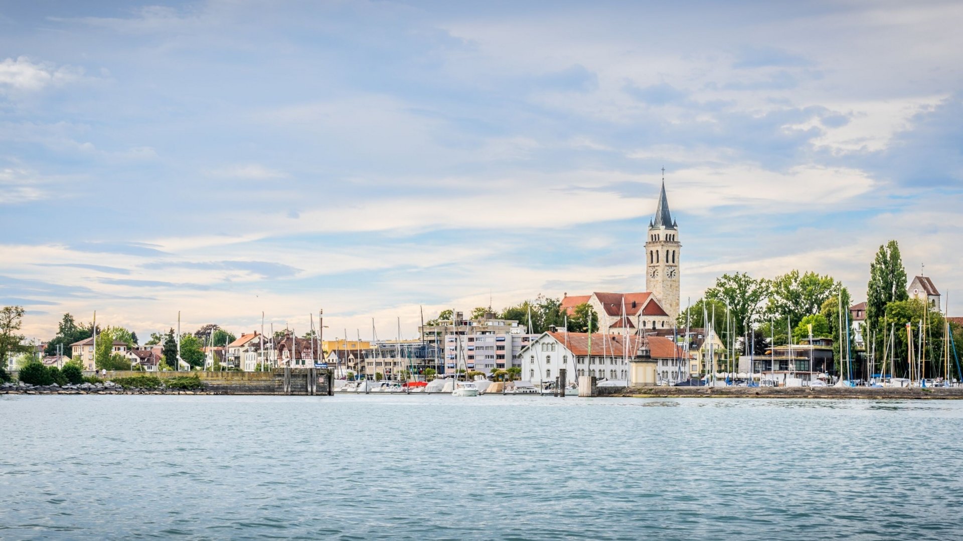 Cityscape with church and boats on water under cloudy sky