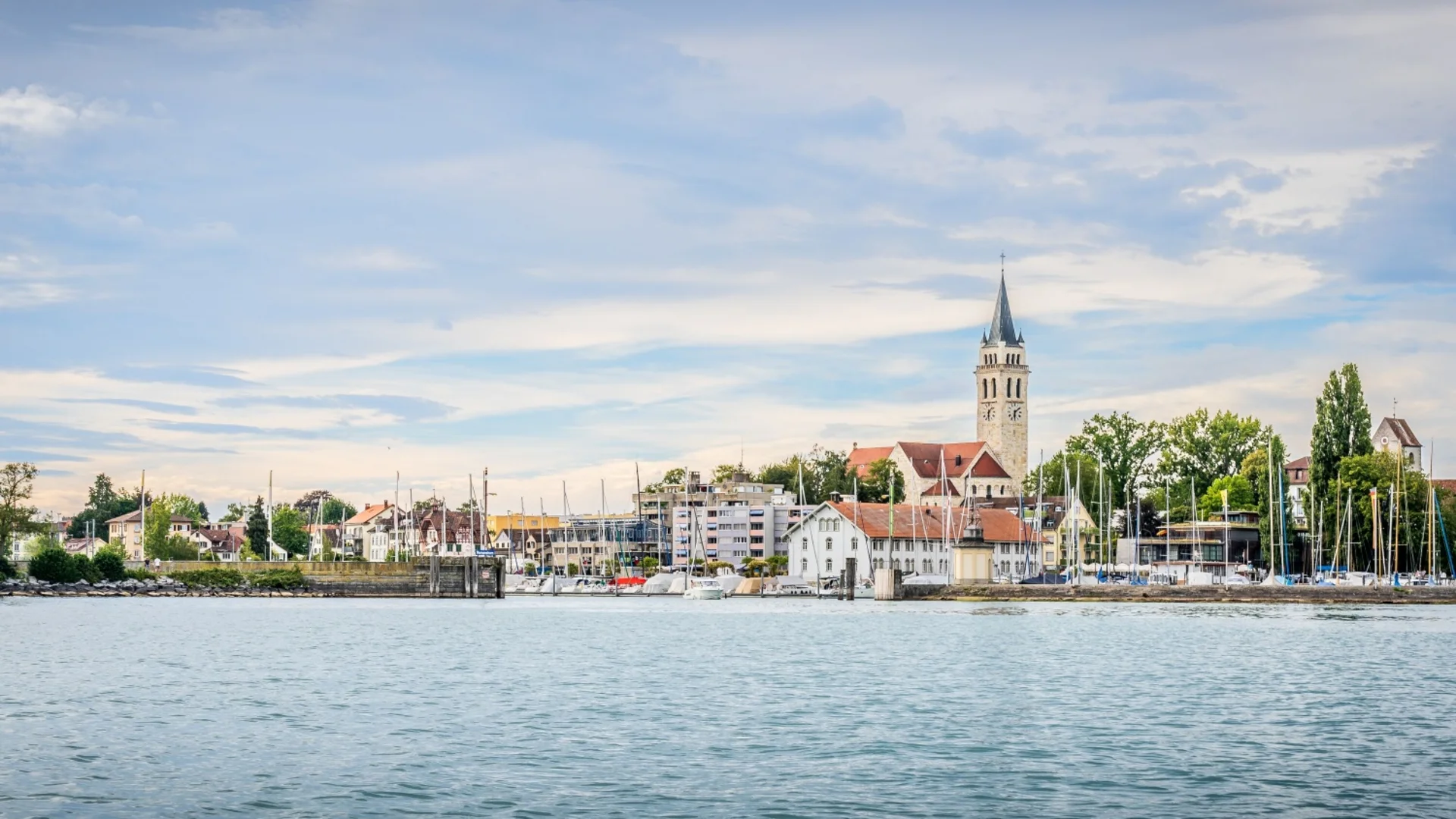 Stadsgezicht met kerk en boten op het water onder bewolkte lucht