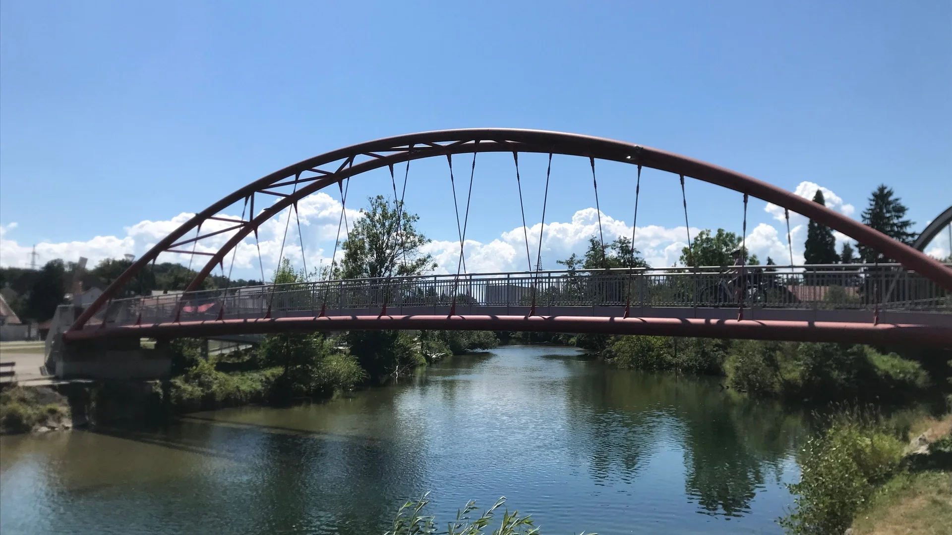 Tour-Detail Rote Bogenbrücke über einen ruhigen Fluss bei klarem Himmel