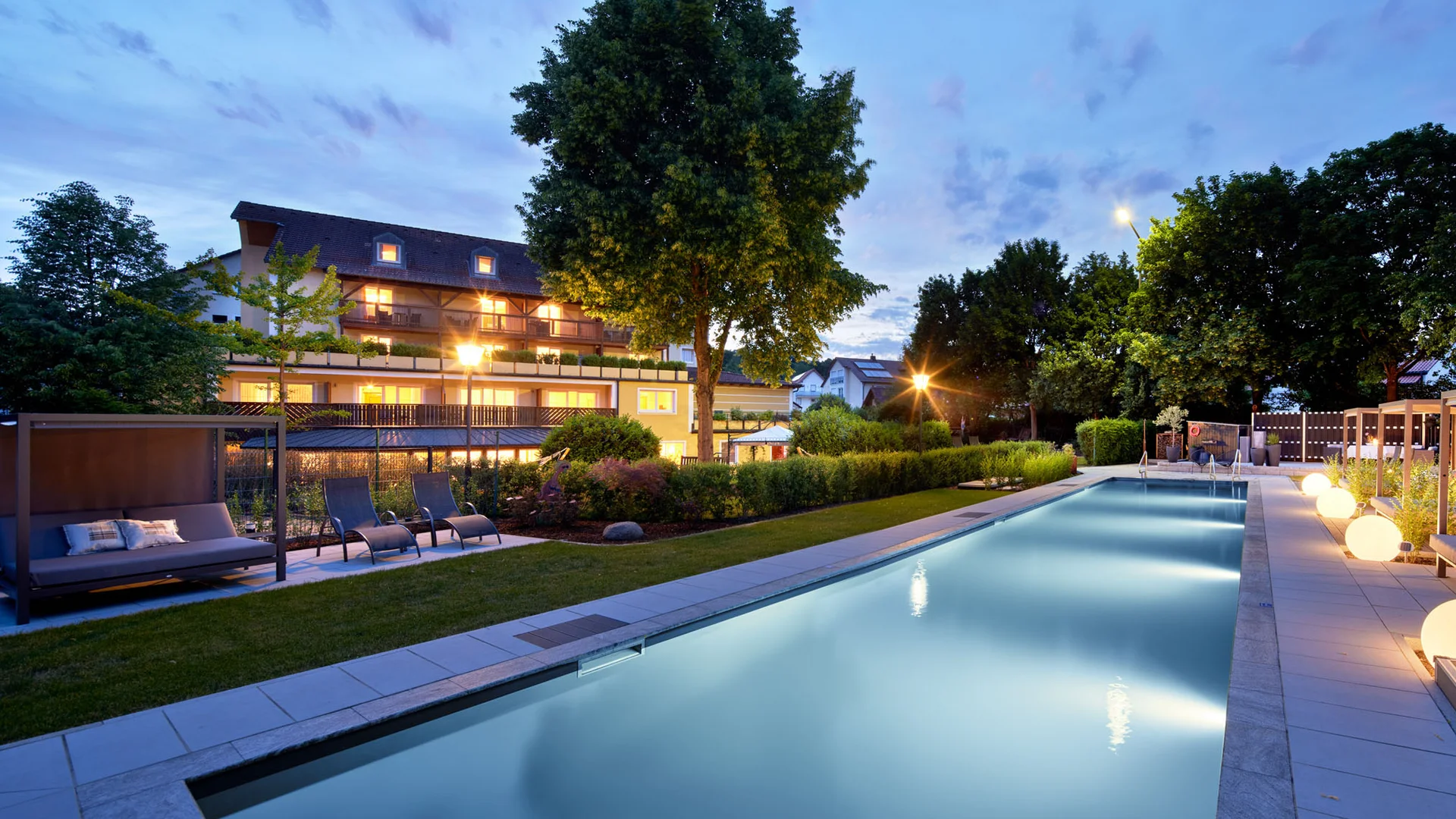 Garden & Spa Hotel das Götzfried **** © Michael Huber Fotographie Verlichte buitenzwembad en tuin van een hotel bij schemering