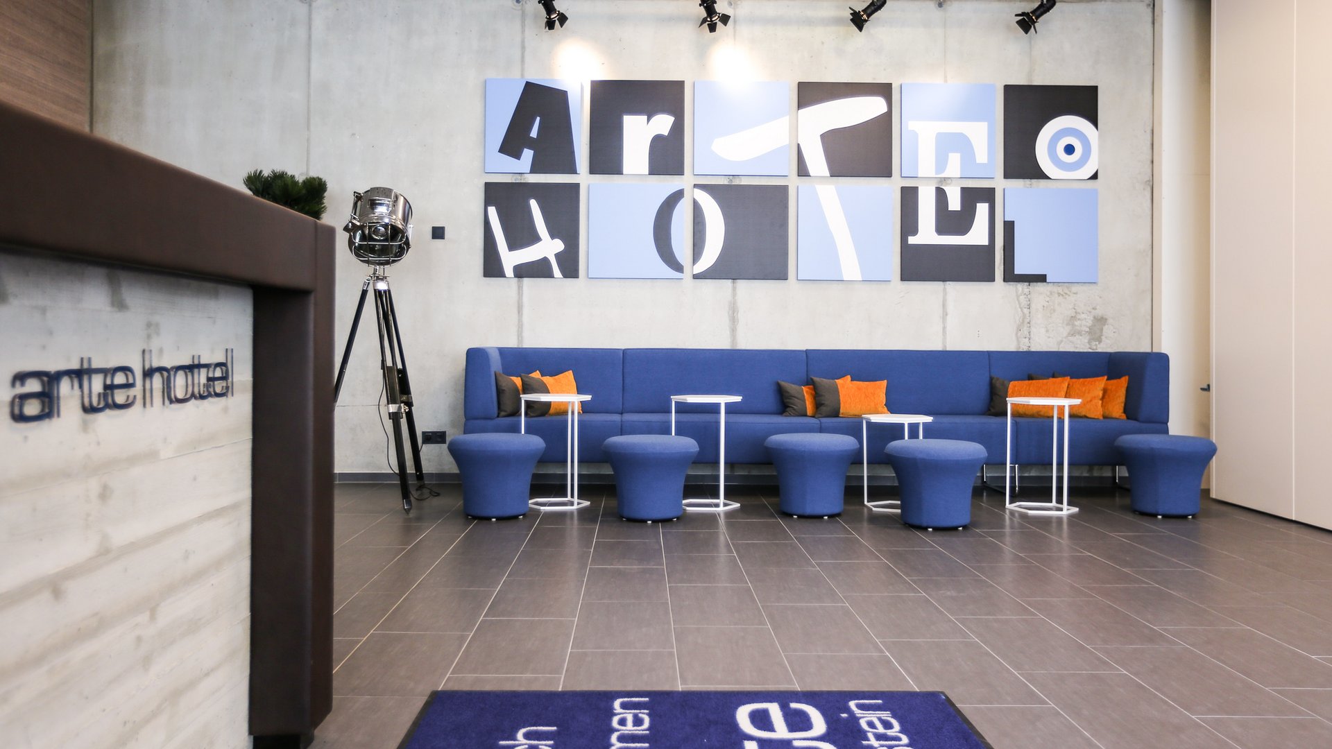 Modern hotel lobby with blue sofa and artwork on concrete wall