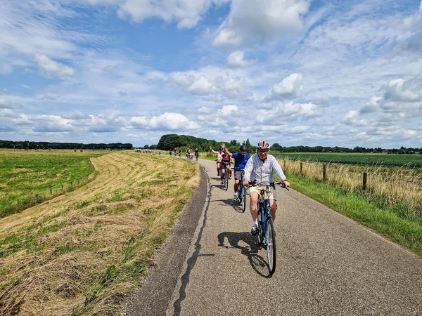 Wo Radfahren & Wasser zusammengehören © Boat Bike Tours Gruppe von Radfahrern fährt auf Landstraße bei bewölktem Himmel