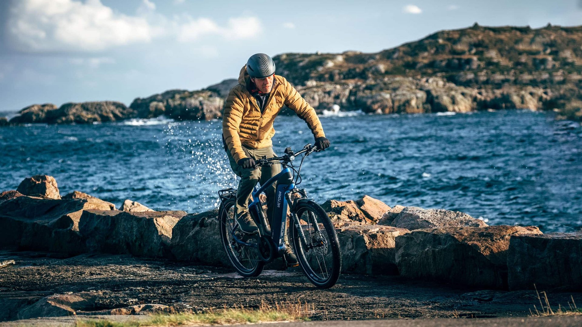 Victoria Man cycling along rocky seaside wearing helmet and jacket