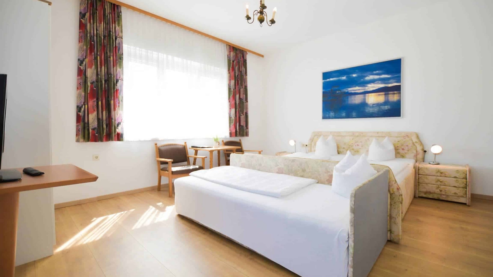 Bright hotel room with double bed, seating area, and large window
