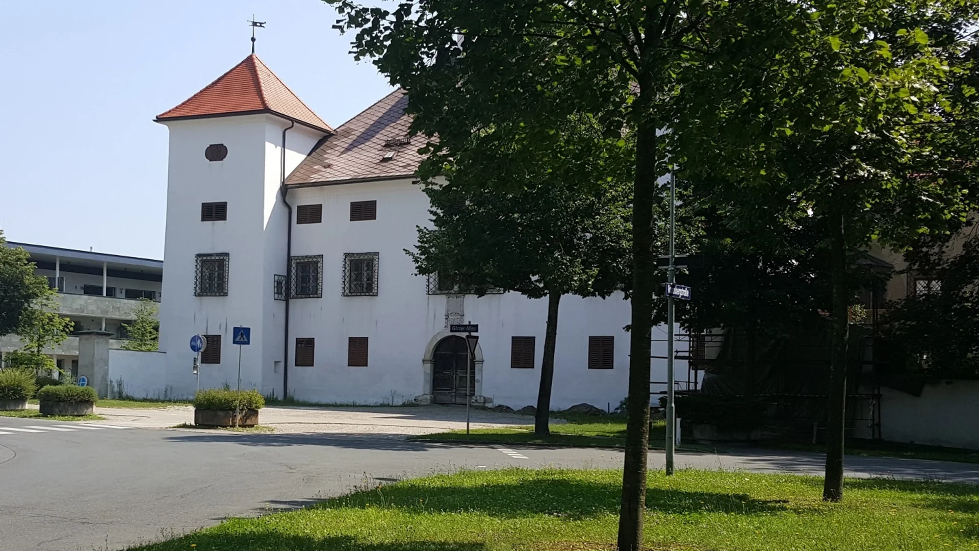 Wit historisch gebouw met rood dak en bomen op de voorgrond