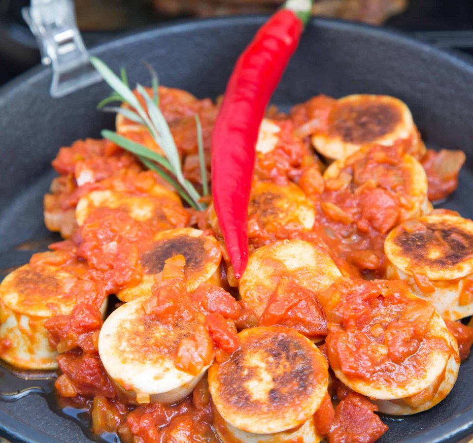 Fried vegan sausages in tomato sauce with red chili in a pan