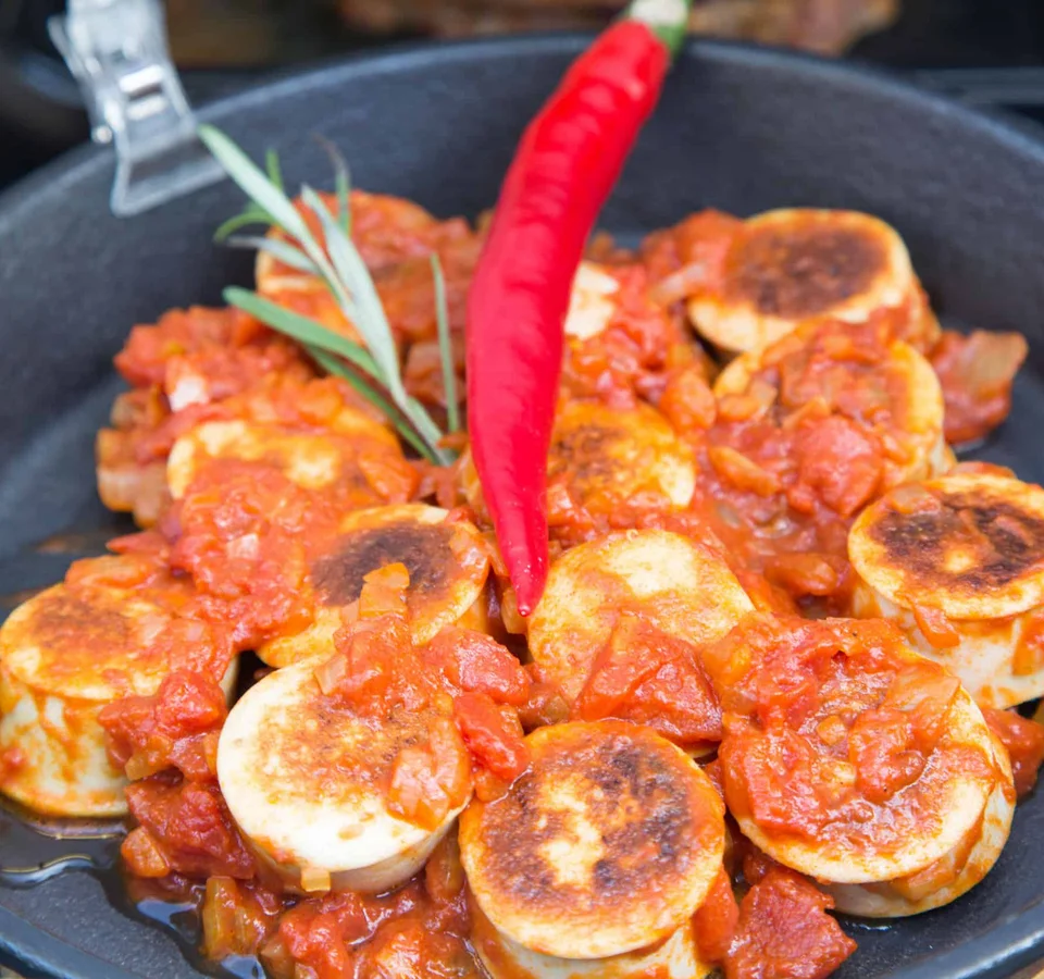 Gebakken veganistische worstjes in tomatensaus met rode chili in pan