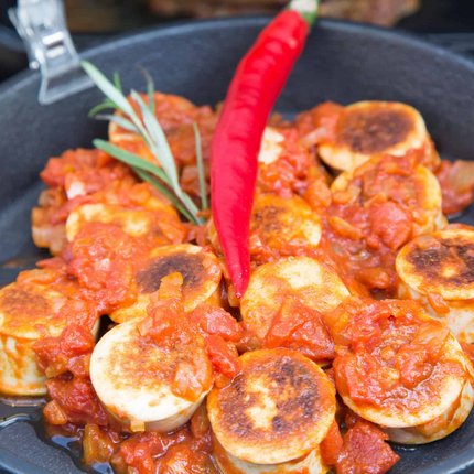 Fried vegan sausages in tomato sauce with red chili in a pan