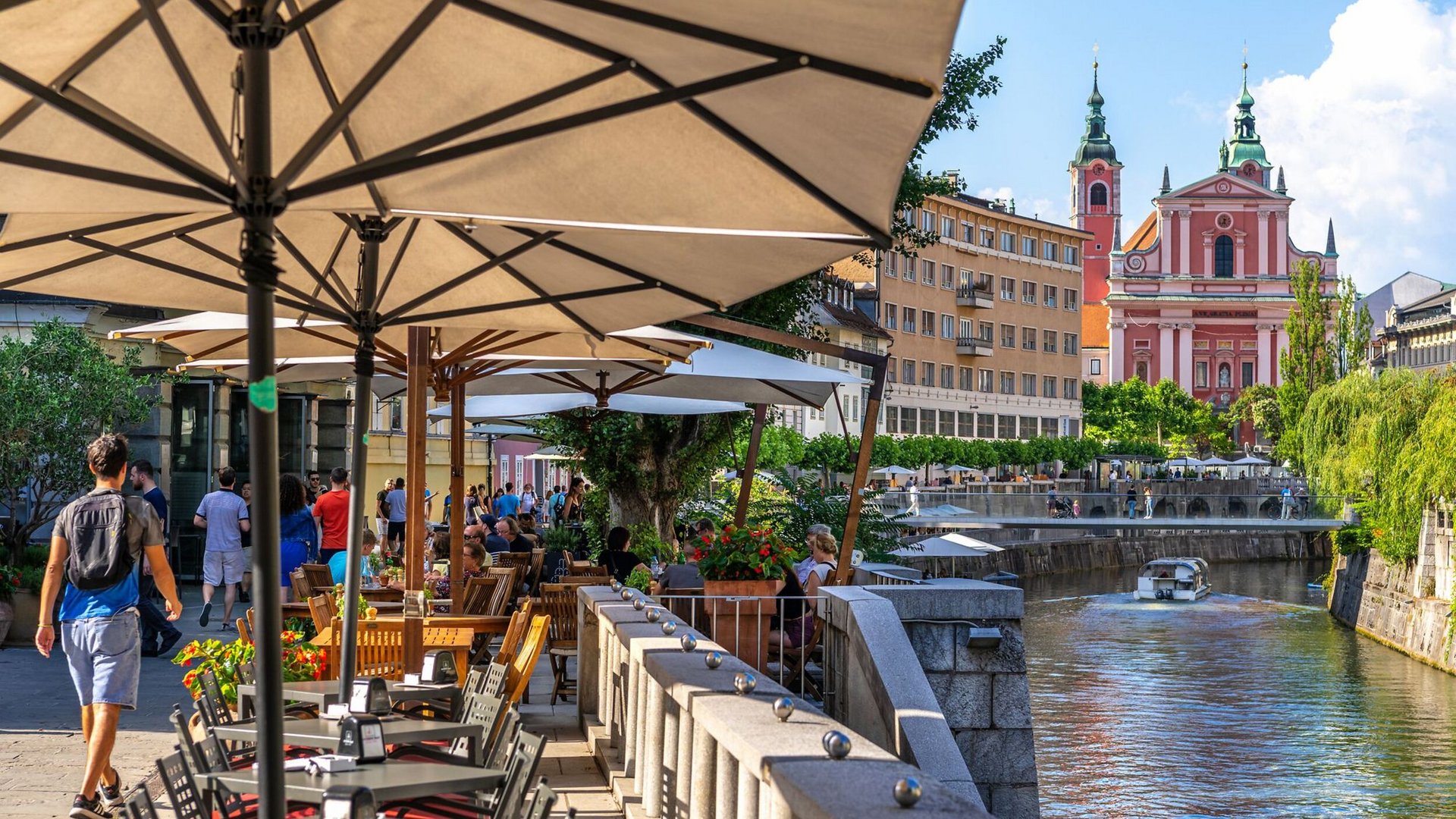 Riverside cafes with church and boat in city under blue sky
