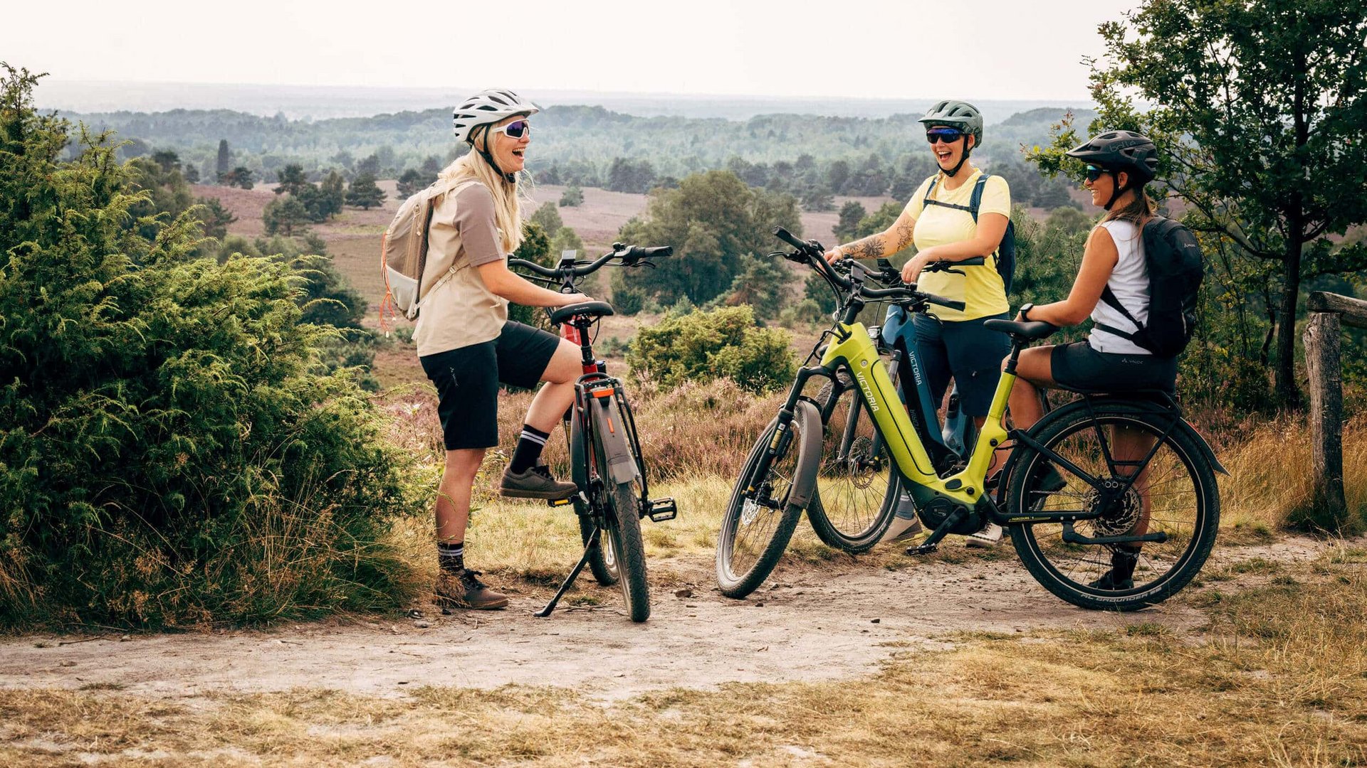 Victoria Three women wearing helmets on bikes taking a break in a scenic outdoor area