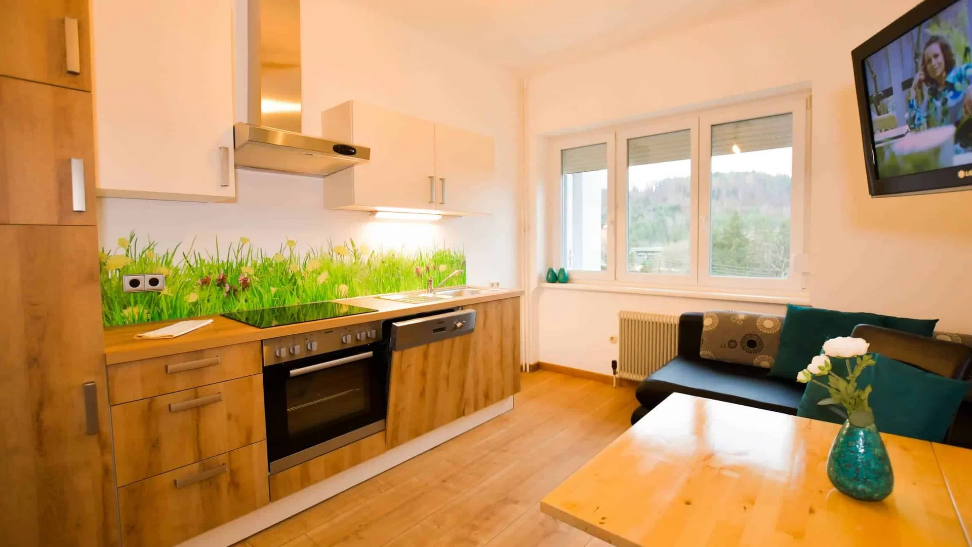 Kleine moderne keuken met houten kasten en bank naast groot raam