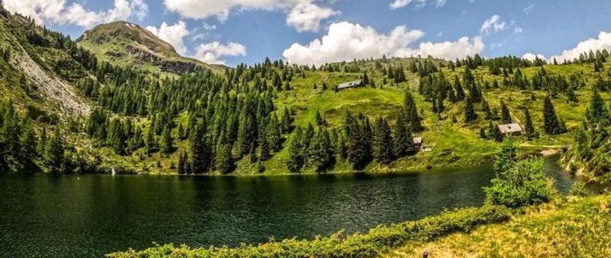 Bicycles lying by a lake surrounded by green mountains under a blue sky