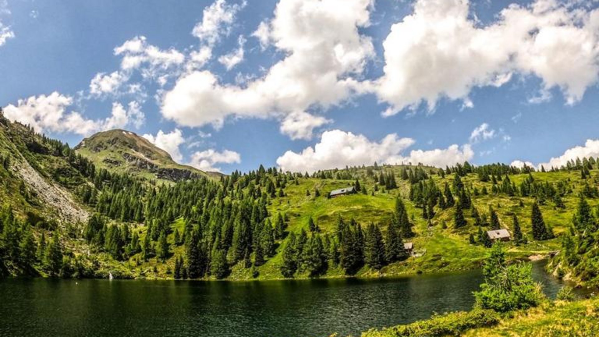 Bicycles lying by a lake surrounded by green mountains under a blue sky
