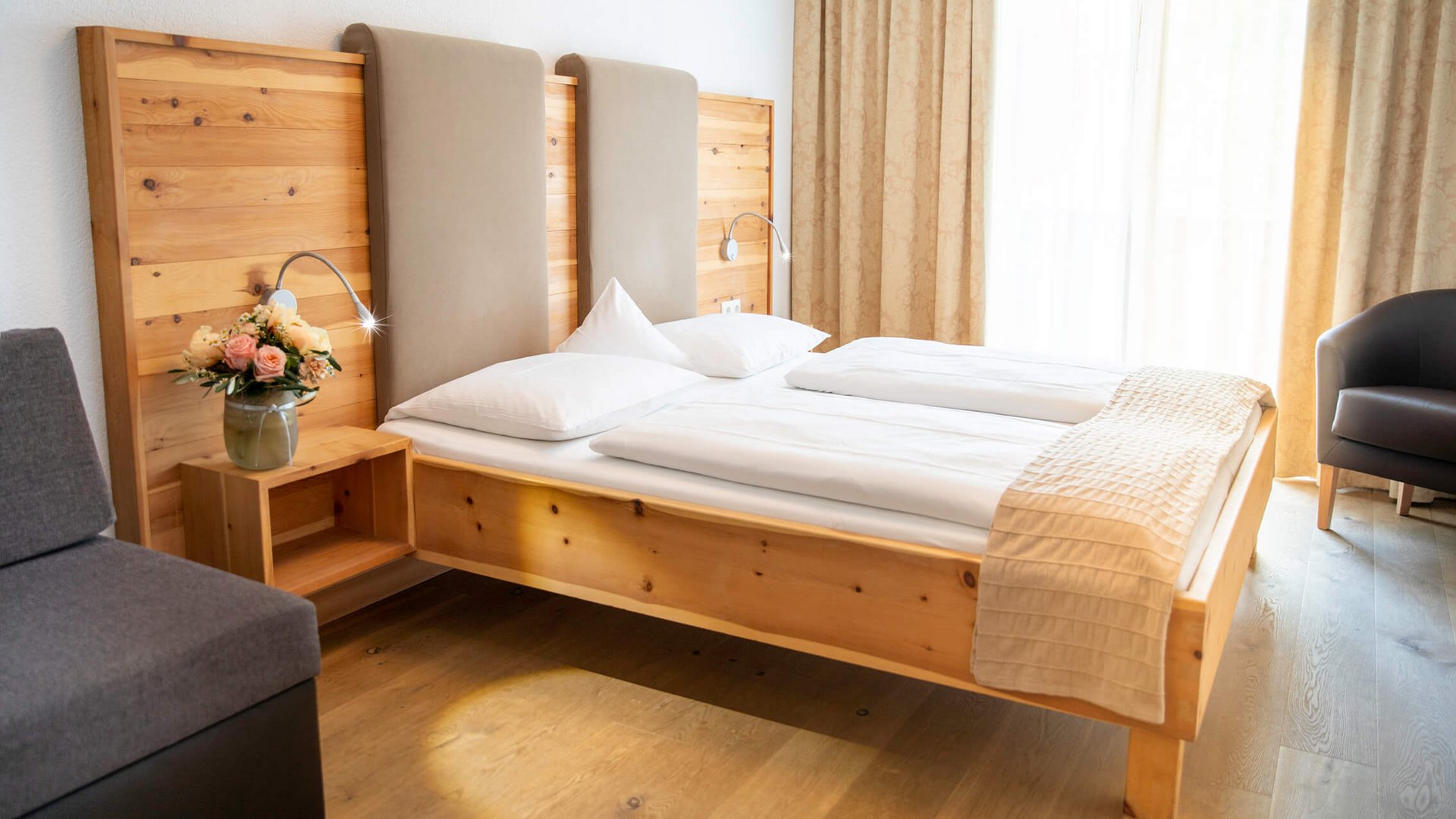 Cozy hotel room with wooden bed and flowers on nightstand