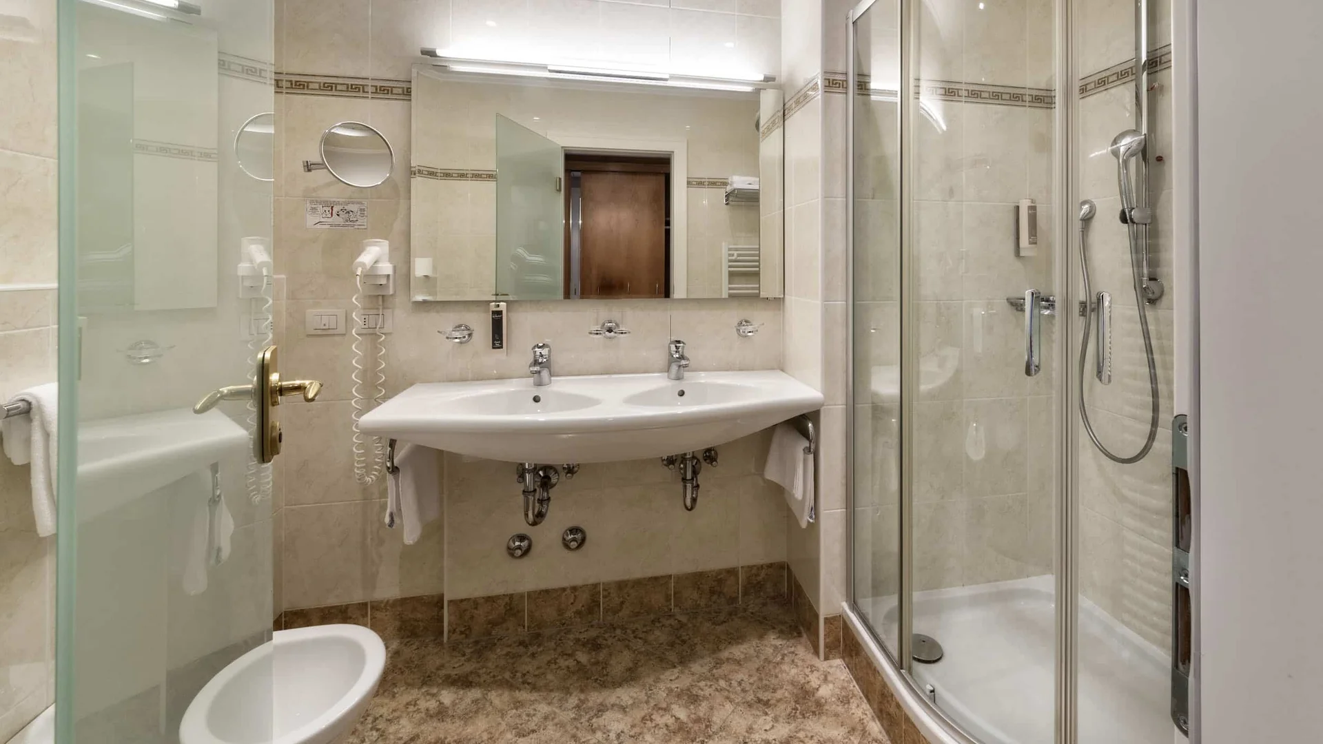 Bright bathroom with double sink and curved glass shower enclosure