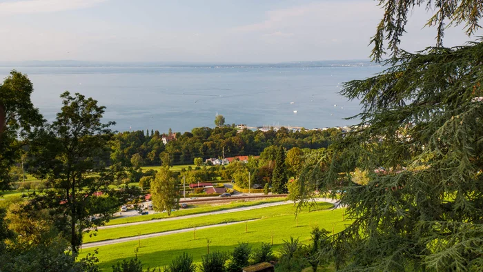 Grüner Hügel mit Blick auf einen See und bewölkten Himmel