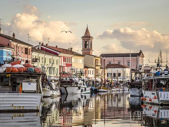Emilia-Romagna © CBV Photo Vissersboten bij kleurrijke huizen en een kerk bij zonsondergang