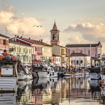 Fishing boats docked along colorful houses and a church at sunset