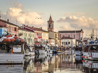 Fishing boats docked along colorful houses and a church at sunset