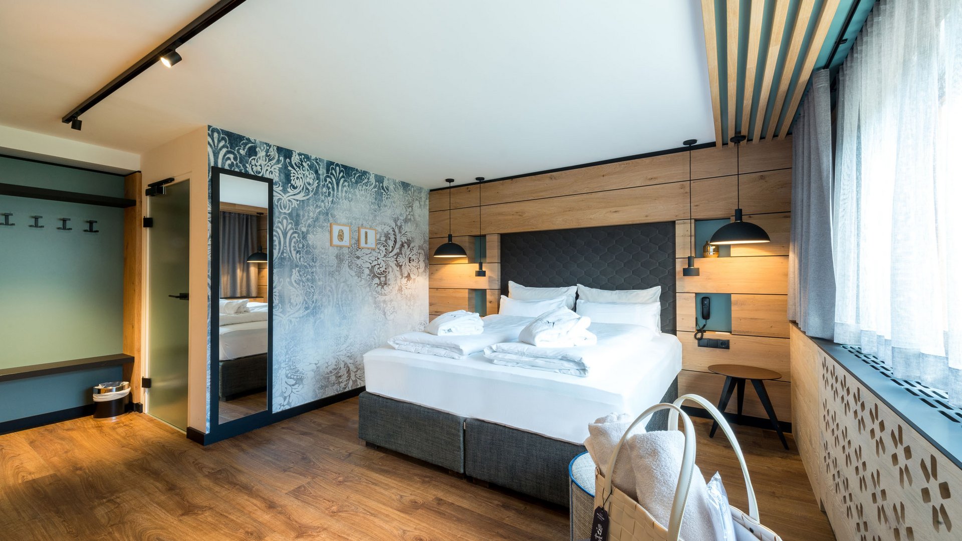 Modern hotel room with double bed, wooden floor, and window with curtains