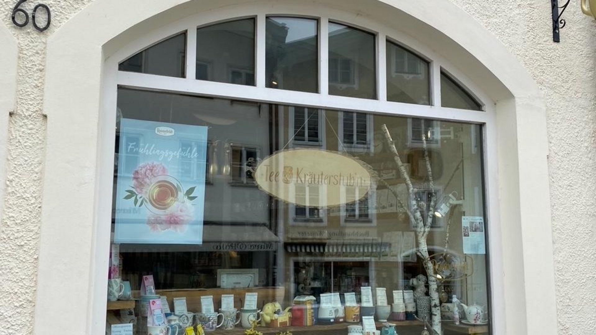 Shop window of a tea store with teapots, cups, and tea varieties