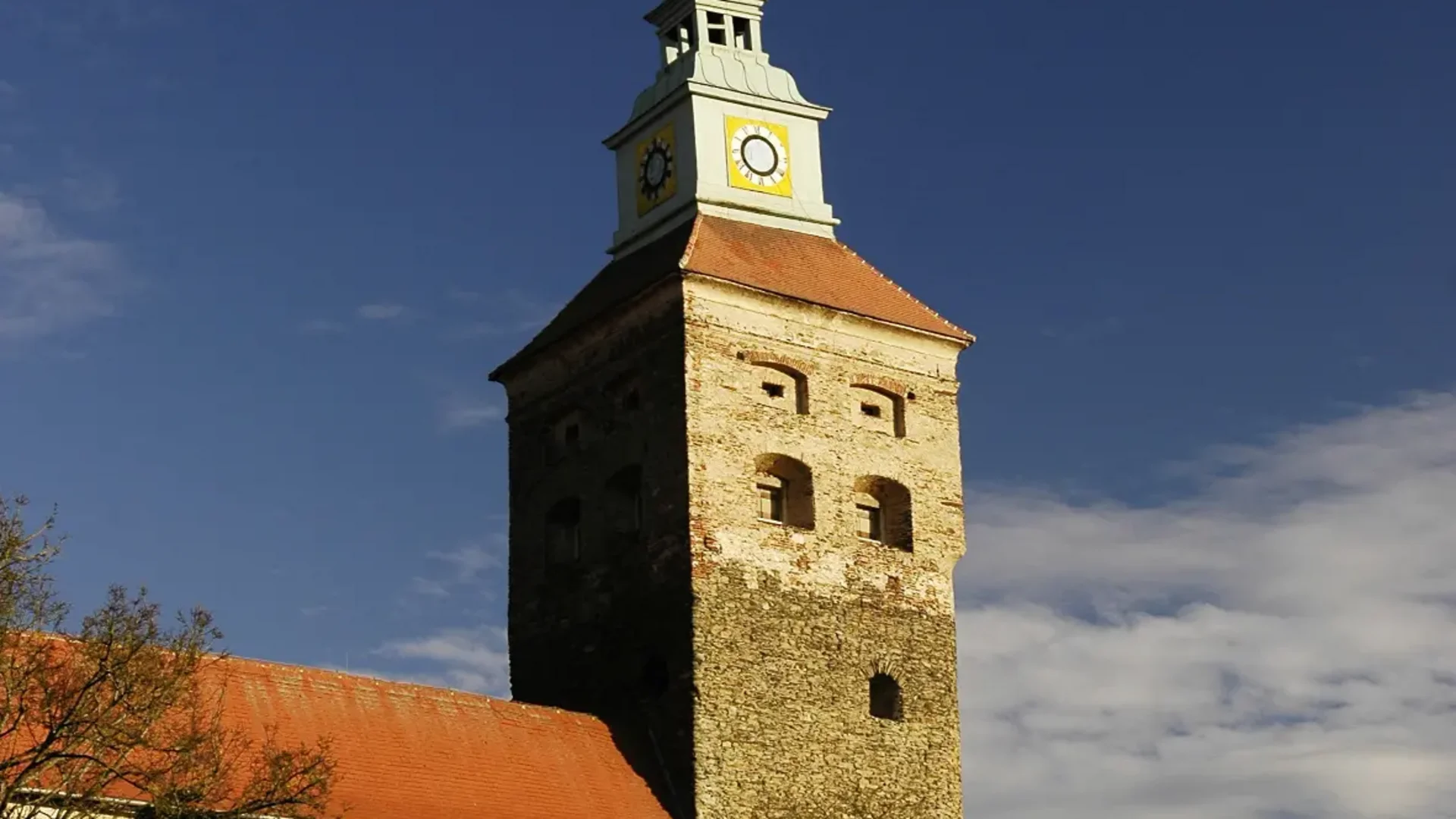 Historischer Uhrenturm eines Steinhauses vor blauem Himmel