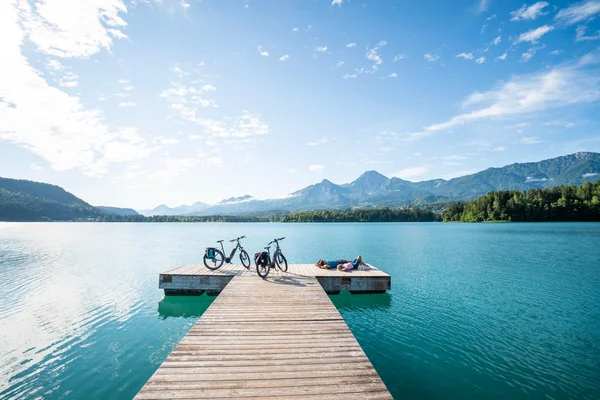 Fietstochten © Kärnten Werbung - Gert Perauer Steiger met fietsen en twee mensen bij helder meer met bergen