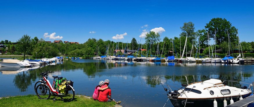 Wallersee fietsroute © Salzburger Seenland - Norbert Eisele-Hein Stel met fietsen aan het meer bij jachten onder heldere blauwe lucht
