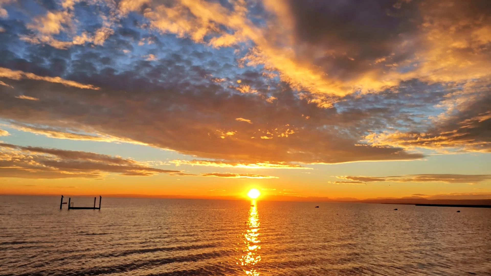 Sonnenuntergang über ruhigem Meer mit Wolken und orangefarbenem Himmel
