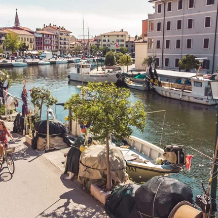 Twee fietsers langs een kanaal met boten en kleurrijke gebouwen in de stad