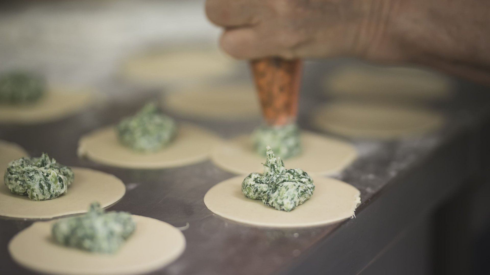 Hand filling ravioli dough with spinach and cheese mixture