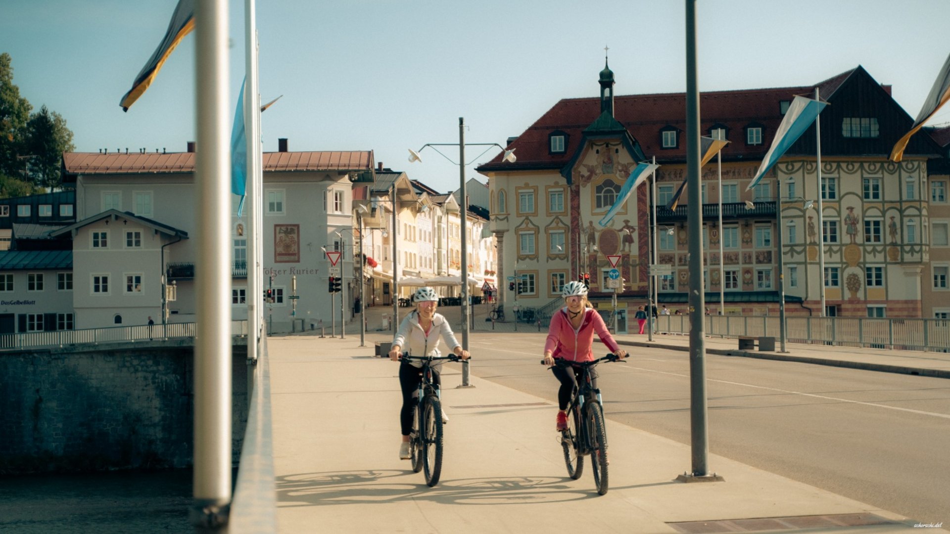 Two women cycling in town with historic buildings on a sunny day