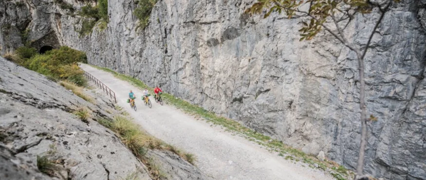 Three cyclists on a path between steep rock walls