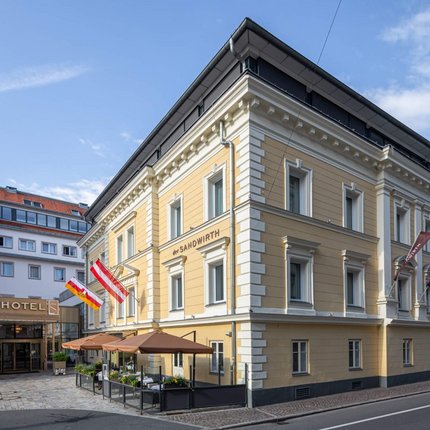 Yellow hotel building with flags and outdoor seating on a sunny day