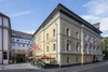 Collective enquiries Yellow hotel building with flags and outdoor seating on a sunny day