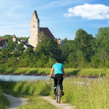Fietser op een pad met kerk en bomen op de achtergrond