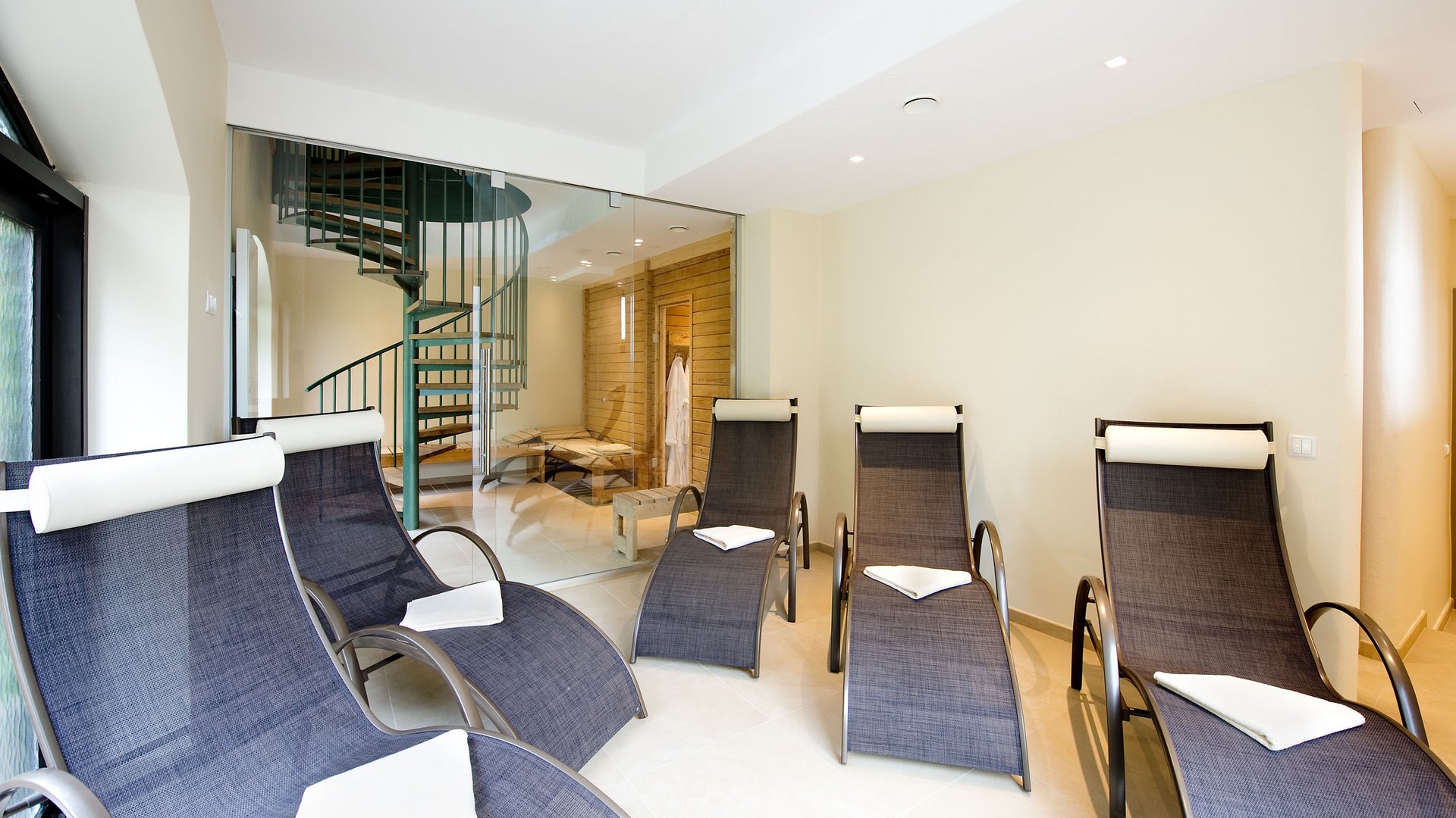 Relaxation room with modern loungers and spiral staircase in the background