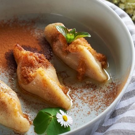 Three filled dumplings topped with cinnamon and butter on a plate