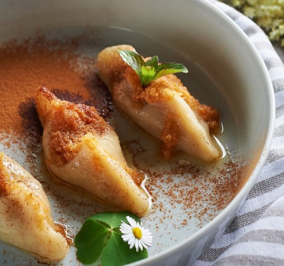 Three filled dumplings topped with cinnamon and butter on a plate