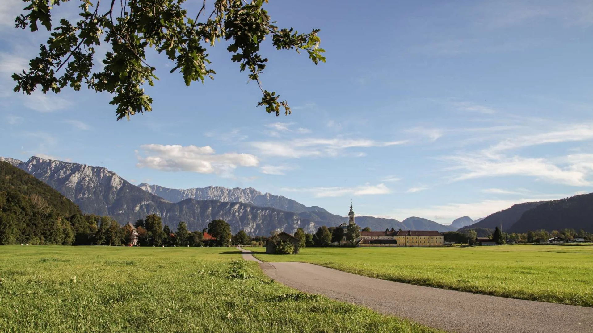 Bergpanorama mit grünem Feld und Kirche unter blauem Himmel