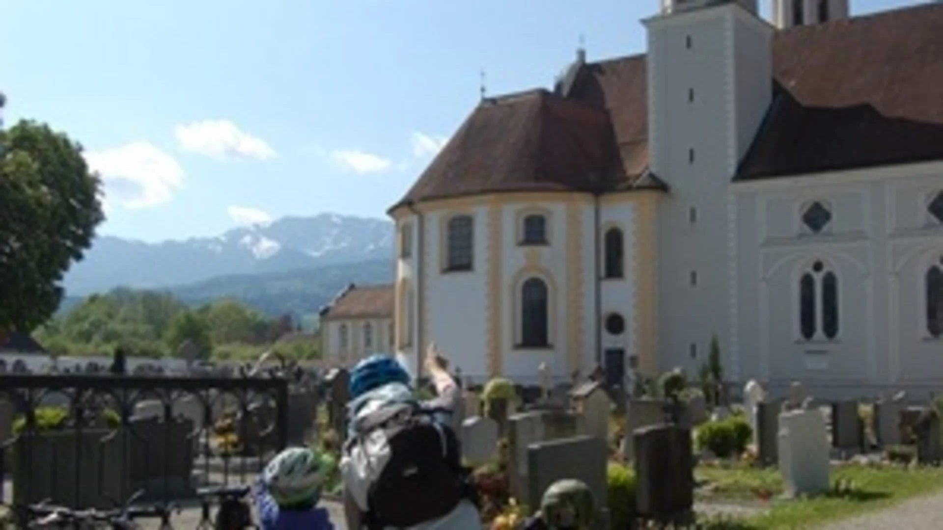 Person mit Kindern auf Fahrrädern vor historischer Kirche mit Zwiebeltürmen