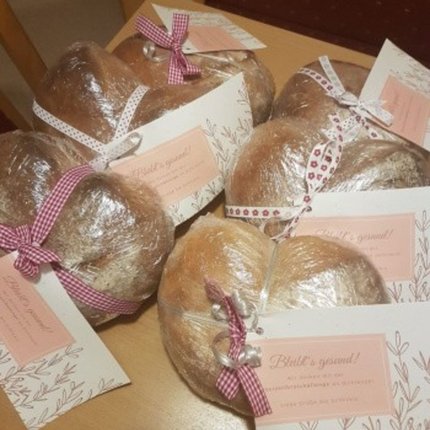 Several heart-shaped breads wrapped with ribbons and greeting cards on a table