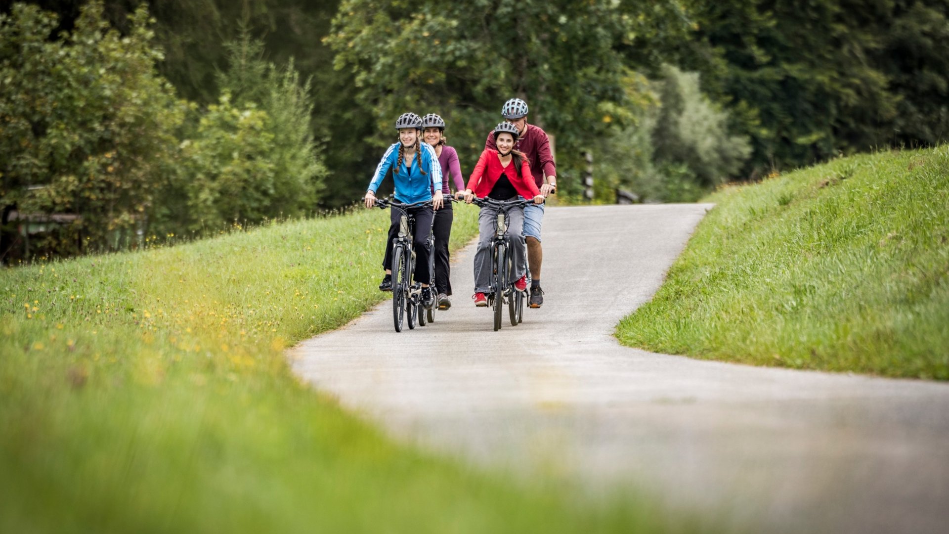 Four people cycling on a path through green countryside