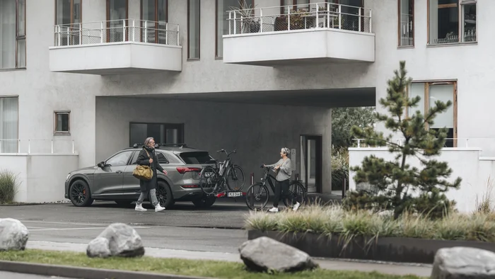 Der Thule Epos © Thule Zwei Personen stehen mit Fahrrädern neben einem SUV vor einem modernen Gebäude