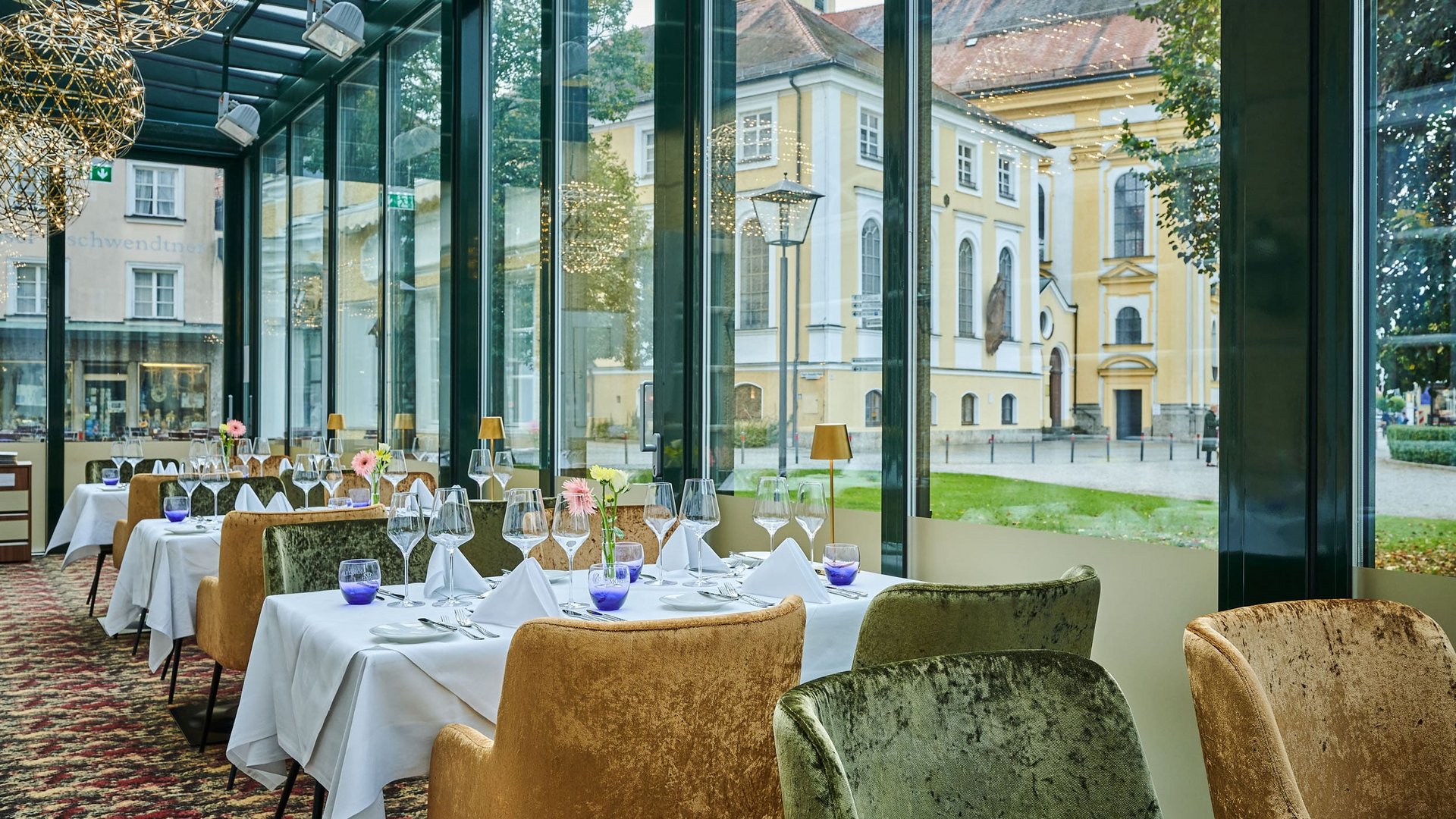 Elegant restaurant with table settings and panoramic windows overlooking historic buildings