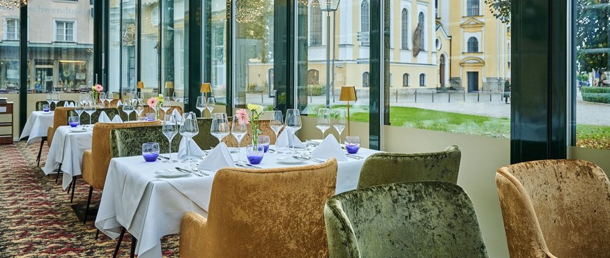 Elegant restaurant with table settings and panoramic windows overlooking historic buildings